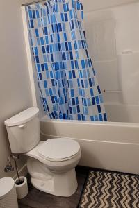 ein Bad mit einem WC und einem blauen Duschvorhang in der Unterkunft MegaVille in Saskatoon + 11 Fotos