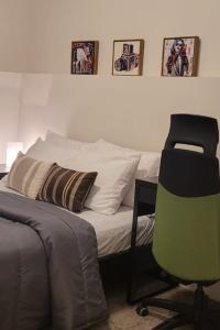 ein Schlafzimmer mit einem Bett und einem grünen Stuhl in der Unterkunft MegaVille in Saskatoon