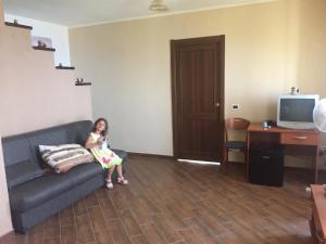 a girl sitting on a couch in a living room at Il Muraglio in Belmonte Calabro +10 photos