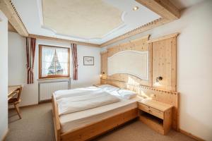 een slaapkamer met een groot bed met een houten hoofdeinde bij Chalet Bel Plan in Ortisei