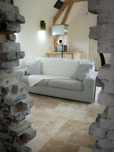 にあるLe Refuge Des Saisonsの白いソファとレンガの壁が備わるリビングルーム