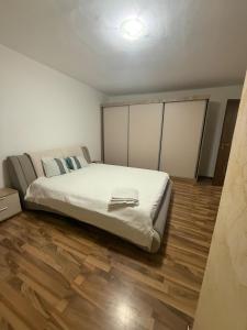 a large bed in a room with a wooden floor at Cozy apartment in Craiova