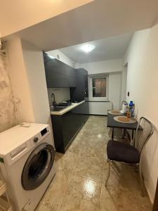 a kitchen with a washing machine and a table at Cozy apartment in Craiova