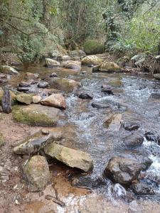 a stream of water with rocks in a forest at Casa Surpresa, Europäisches Flair in São José dos Campos
