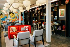 a library with a red couch and chairs at citizenM Copenhagen Radhuspladsen in Copenhagen +26 photos
