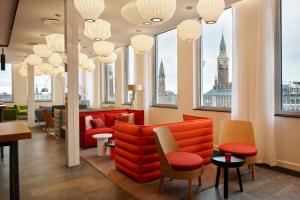 a waiting room with red chairs and windows at citizenM Copenhagen Radhuspladsen in Copenhagen