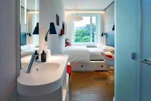 a bathroom with a sink and a bedroom with a bed at citizenM Zürich in Zürich
