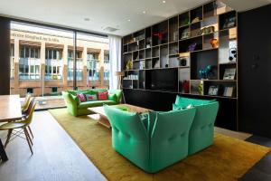 een woonkamer met groene stoelen en een tafel bij citizenM Glasgow in Glasgow