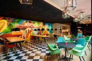 a restaurant with tables and chairs and a colorful wall at citizenM Paris Gare de Lyon in Paris
