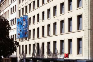 a tall white building with a blue banner on it at citizenM Geneva in Geneva