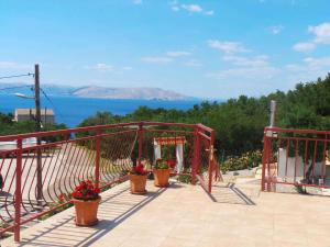 a deck with potted plants and a gate with a view of the water at Apartments in Sveti Juraj 27785 in Burnjak