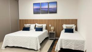 two beds in a room with blue pillows at 407-3 · Duplex Sossego in Anápolis
