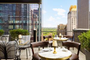 a balcony with tables and chairs and a view of a city at Le Meridien New York, Central Park in New York
