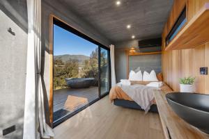 a bedroom with a tub and a bed and a large window at Luxury Container and Cabin with Outdoor Bath in Wanaka