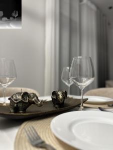 une table avec deux verres à vin et une assiette décorée d'éléphants. dans l'établissement Arjola Cozy Stay, à Korçë
