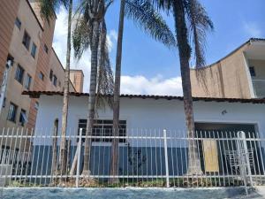 a white fence in front of a building with palm trees at Home office solteiro aconchegante no Centro de Poços de Caldas in Poços de Caldas