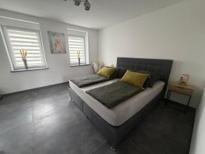 a bedroom with a bed with yellow pillows and two windows at Mira Suites 1 in Schwalbach