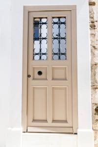 a white door with a window on a building at 4TWaves Pyrgos House -near the square Platanos in Pánormos