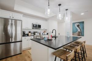 a kitchen with a refrigerator and a counter with chairs at Lowcountry Landing! 3-story Townhouse in Old Town's Promenade in Bluffton +32 photos