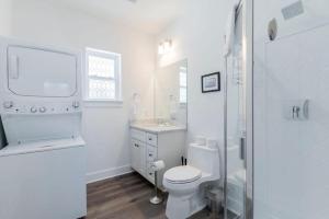 a white bathroom with a toilet and a sink at Charming Old Town Loft, nestled in the Heart of Historic Bluffton, SC in Bluffton +15 photos