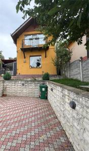 a yellow house with a window and a brick driveway at Casa Alex in Hunedoara +5 photos