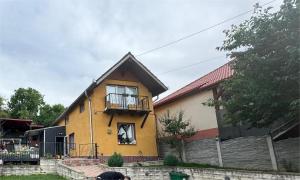 Una casa amarilla con balcón en la parte superior. en Casa Alex, en Hunedoara 5 fotos más