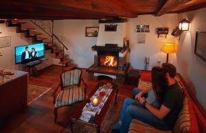 a woman sitting on a couch in a living room with a fireplace at Brvnare - Ranč Platan in Vrdnik