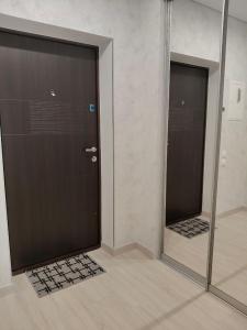 Ein Badezimmer mit Spiegel und einer Tür, in der sich das Duschbild spiegelt in der Unterkunft New Comfort Apartment in Hostomelʼ