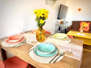 a table with plates and a vase with yellow flowers at New flat close to center in Komárov