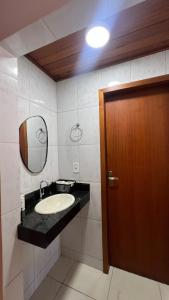 a bathroom with a sink and a wooden door at Casa - Guarapari in Guarapari +33 photos