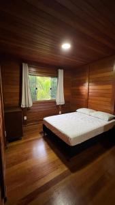 a bedroom with a large bed in a wooden room at Casa - Guarapari in Guarapari