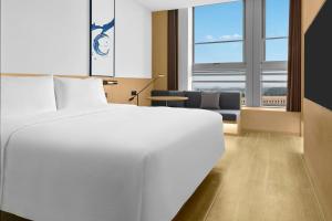 een slaapkamer met een groot wit bed en een bank bij Fairfield by Marriott Yancheng Dafeng in Yancheng +31 foto's