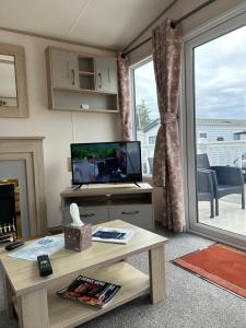 ein Wohnzimmer mit einem TV und einem Tisch mit einem Tisch in der Unterkunft Haven Blackpool Fleetwood holiday park in Fleetwood