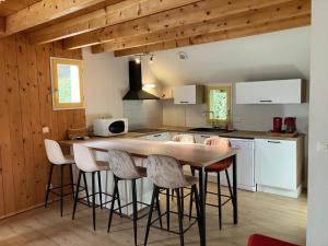 una cocina con una gran mesa de madera y taburetes en Residence des oiseaux, en Lesponne
