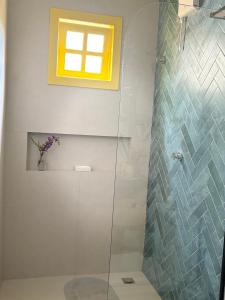 un bagno con doccia in vetro con finestra di Villa Tropicana a Saubara Altre 5 foto