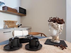 a table with a vase with coffee cups on it at Cielo Cagliari For2 Design - Comfort Solo Adulti in Cagliari