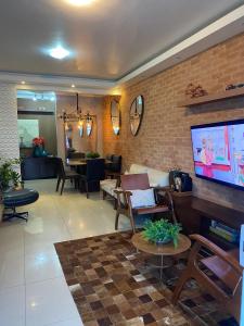 ein Wohnzimmer mit Couch und Flachbildfernseher in der Unterkunft Casa top pertinho da praia com piscina e área gourmet in Arraial do Cabo