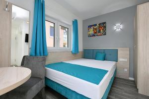 a bedroom with a large bed with blue curtains at City-Hotel Zuffenhausen - Apartments in Stuttgart