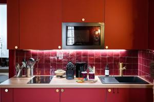 a kitchen with red cabinets and a sink at Chai numéro 12, une immersion au coeur du vin in Bergerac +34 photos