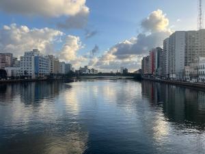 a river in a city with tall buildings and clouds at Lindo Nascer do Sol in Recife