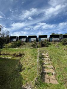 un grupo de edificios en una colina con un campo de césped en Huillín Lodge, en Huillinco
