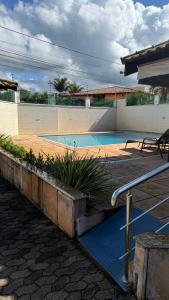 a swimming pool with blue water and plants at Casa Rocha in Porto Seguro
