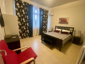 a bedroom with a bed and a red couch at Nefele - Athens Airport Home in Artemida