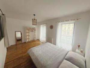 a white bedroom with a bed and a window at Quimper: T3 avec vue cathédrale proche gare in Quimper
