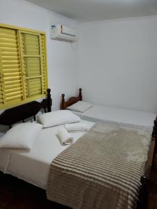 two beds in a white room with a basketball hoop at Hotel Linassi in Cruz Alta