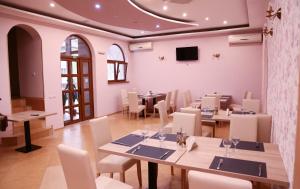 a dining room with tables and chairs and a tv at Hotel Apollonia in Braşov