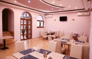 a dining room with tables and chairs and a tv at Hotel Apollonia in Braşov