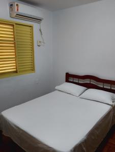 two beds in a white room with a window at Hotel Linassi in Cruz Alta