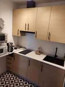 Una cocina con armarios de madera, fregadero y microondas. en La bóveda, en Zafra