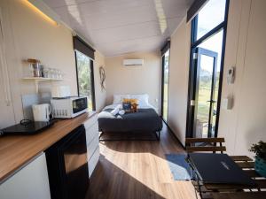 Doyles CreekBundaleer Tiny House 2 by Tiny Away的客房设有一张床和一间带窗户的厨房 更多24张照片